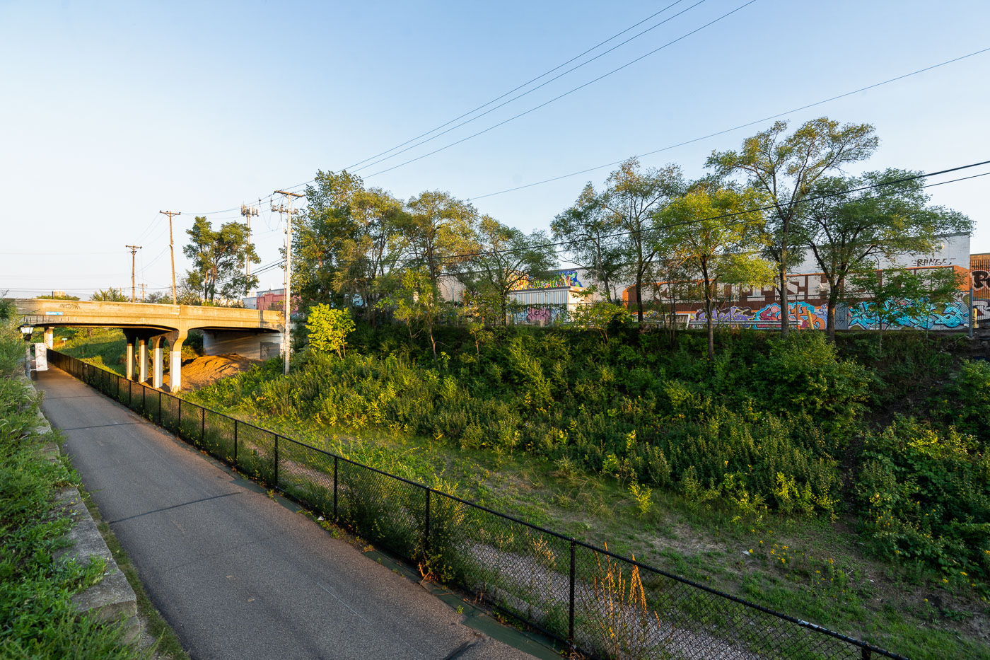 Midtown Greenway bike path in Minneapolis passes under an overpass and alongside buildings decorated with graffiti art.