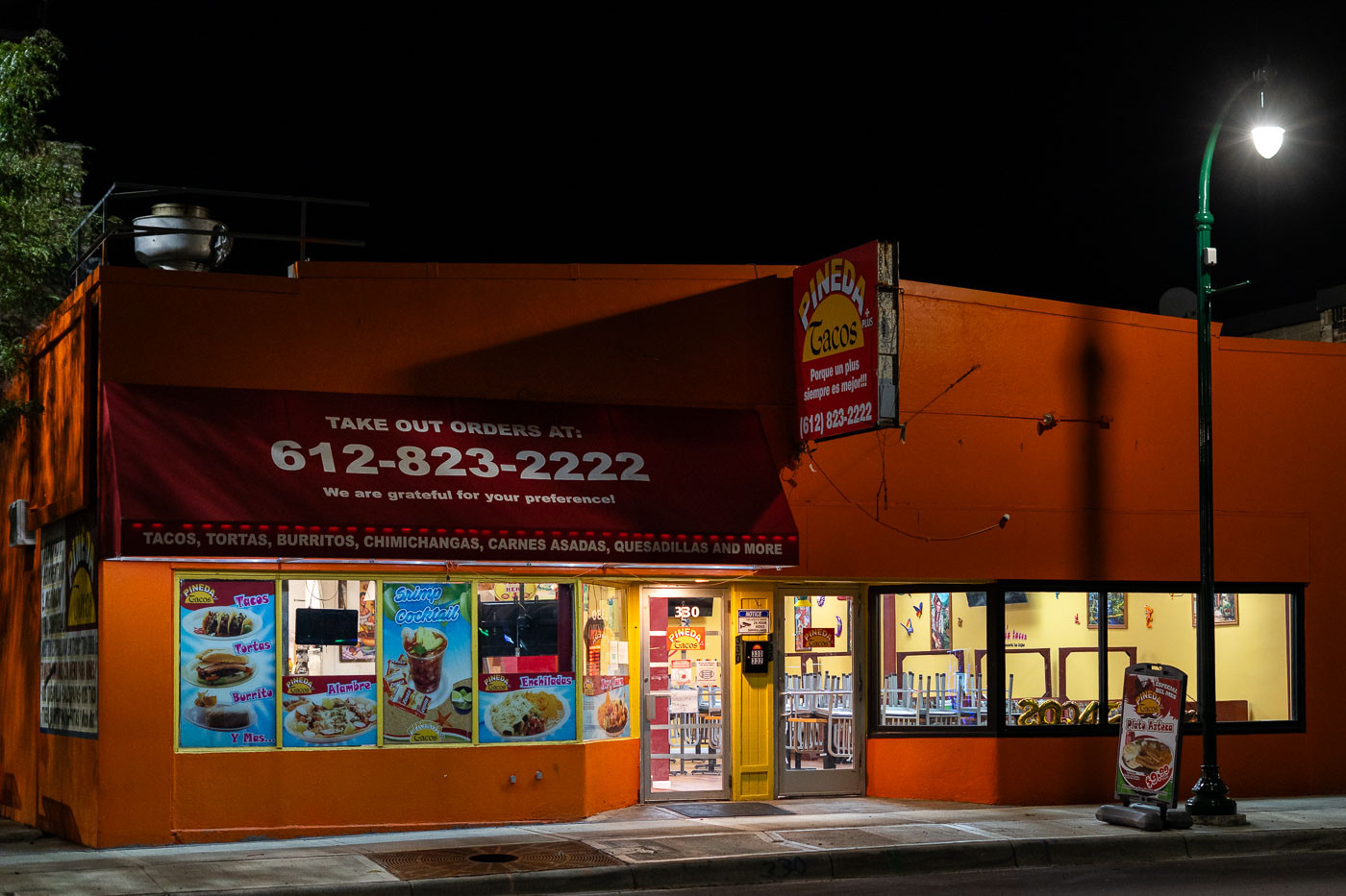 Pineda Tacos, a Mexican restaurant, is illuminated at night on East Lake Street in Minneapolis, offering tacos, tortas, and burritos.