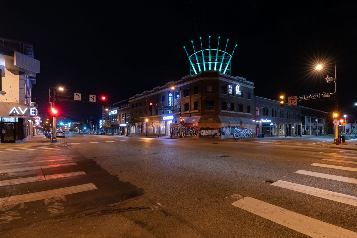 Seven Points Mall at Hennepin and Lake covered in boards. One board reading "Deona Marie", Deona Marie was killed on June 13th, 2021 when a man drove through barricades put in place by protesters.