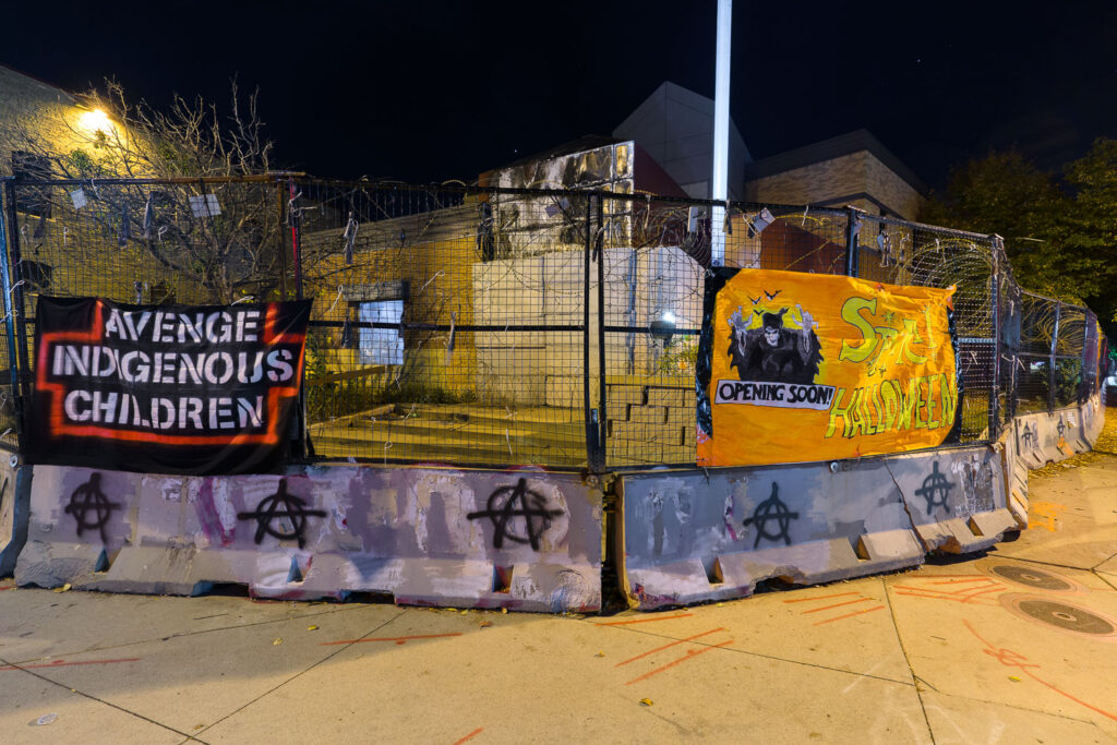 "Avenge Indigenous Children" and "Spirit Halloween" banners on the former Minneapolis Police Third Precinct.
