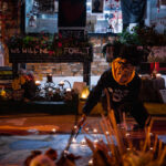 A caretaker at George Floyd Square lights candles at the George Floyd Memorial.