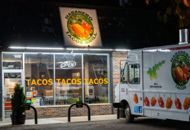 Habanero Tacos Grill glows along East Lake Street late into the evening, with its bright “TACOS TACOS TACOS” window lettering and a branded food truck parked out front. The restaurant reflects the long-standing presence of Latino food culture on the corridor, where small family-run kitchens, taquerías, and mobile food vendors have shaped the visual and culinary identity of the neighborhood.

Located along a stretch of Lake Street known for immigrant-owned businesses and tightly packed storefronts, the shop sits within a commercial landscape rebuilt and revitalized multiple times over the past century. Despite economic shifts and recent reconstruction efforts, the area remains a hub of diverse restaurants and community-oriented businesses, with places like Habanero Tacos Grill continuing to anchor the corridor’s daily life.