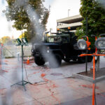 A military type vehicle parked behind layer of fencing and lights outside of Seven Points mall.