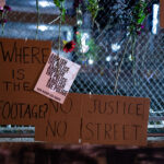 Protest signs hanging on the fencing around Seven Points Mall where Winston Smith was killed by law enforcement 4 months prior.