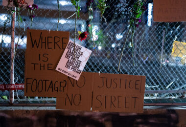 Protest signs hanging on the fencing around Seven Points Mall where Winston Smith was killed by law enforcement 4 months prior.