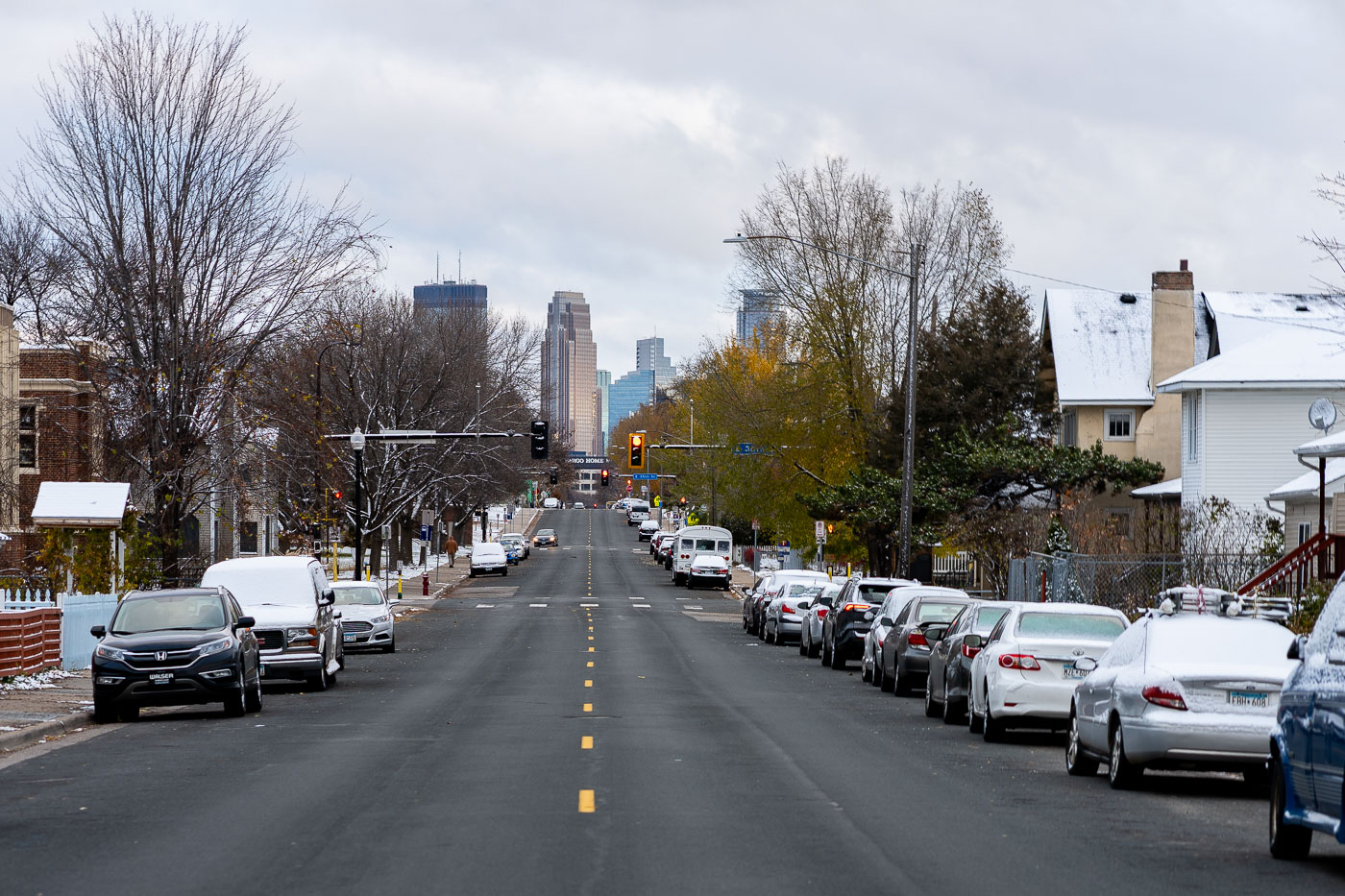 4th Avenue South in Minneapolis, Minnesota, looking north towards the downtown skyline. Snow dusts the street and parked cars on this major thoroughfare connecting residential areas to the business district.