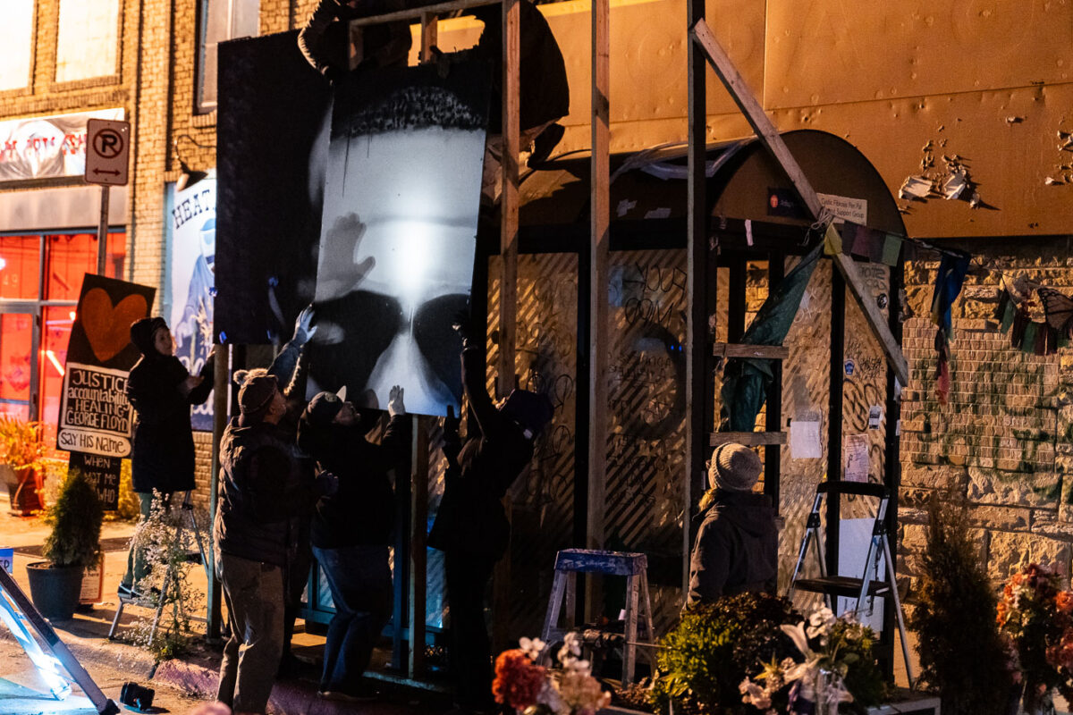 Artists and community members help remove the George Floyd mural prior to snow arriving.
