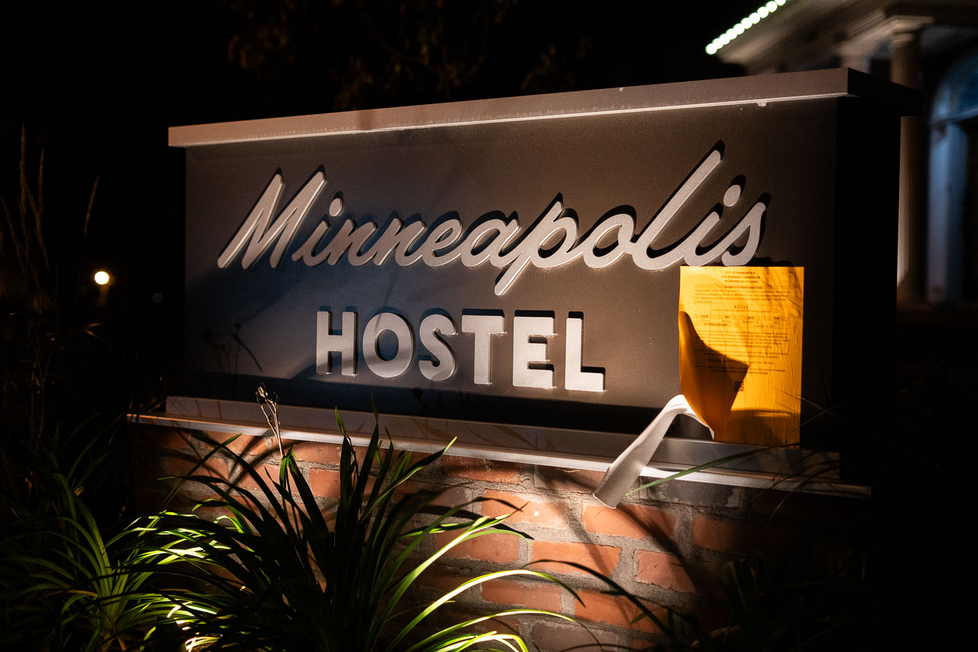 The illuminated Minneapolis Hostel sign is visible at night, marking a location for affordable lodging in the city.