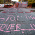 Protesters paint "Stop The Cover Up" outside the parking garage where Winston Smith was killed by law enforcement 5 months earlier.