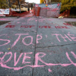 Protesters paint "Stop The Cover Up" outside the parking garage where Winston Smith was killed by law enforcement 5 months earlier.