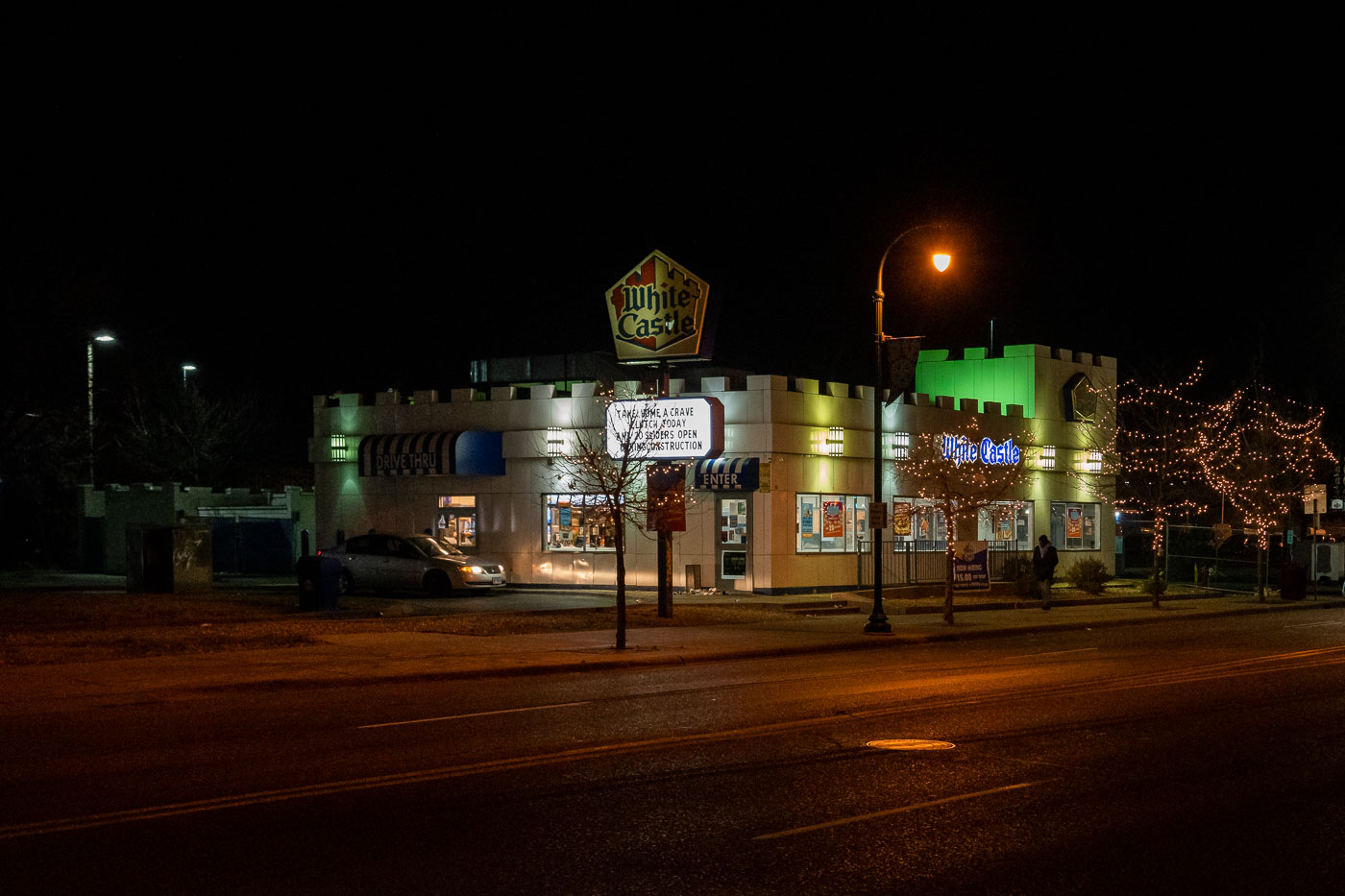 The White Castle restaurant on Lake Street in Minneapolis is illuminated at night, featuring its signature crenellated facade.