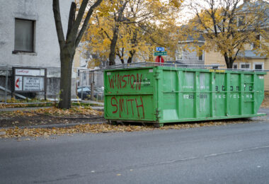 A dumpster with "Winston Smith" written on it. Smith was shot and killed by a federal task force on top of the parking garage across the street.