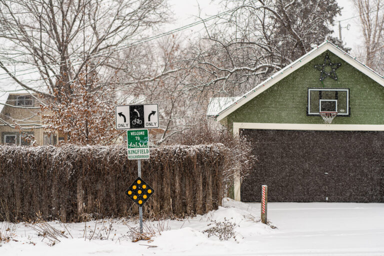 Fresh snowfall in Kingfield Minneapolis 1 Welcome to Kingfield Neighborhood sign in Minneapolis during a December snowstorm.