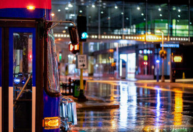 A Metro Transit bus crossing Marquette Ave in downtown Minneapolis on a rainy December night.
