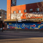 Boards painted "We're Open" on Hufan Restaurant & Cafe on Lake Street. Transtifa graffiti on the second floor.