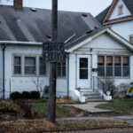 A George Floyd sign hangs on a street pole in South Minneapolis. A yard sign reading "No Justice No Streets" in the yard.