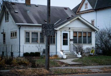 A George Floyd sign hangs on a street pole in South Minneapolis. A yard sign reading "No Justice No Streets" in the yard.