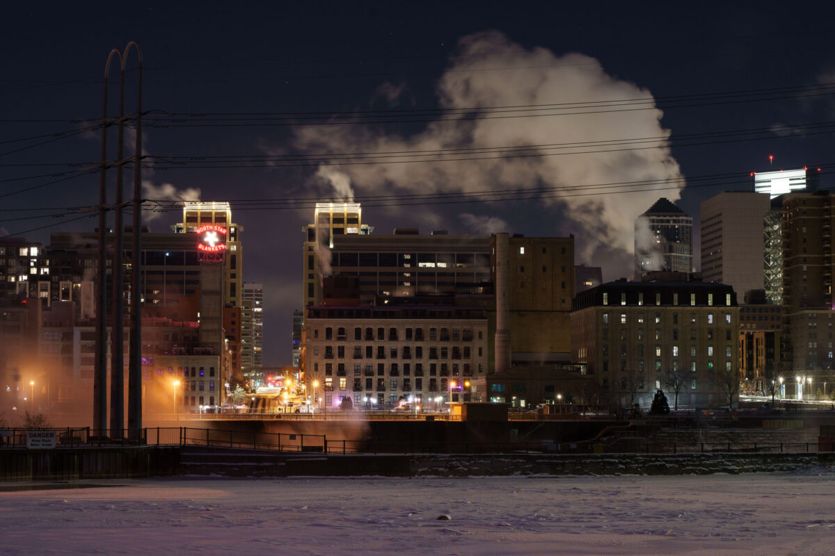 Minneapolis riverfront at night with the North Star Blankets sign and steam over the Mississippi River