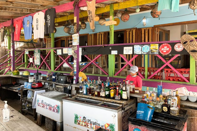 Bar at Pirates, Secret Beach, Ambergris Caye 2 Pirates at Secret Beach bar in Ambergris Caye, Belize, with colorful wood structures and liquor bottles on counter.