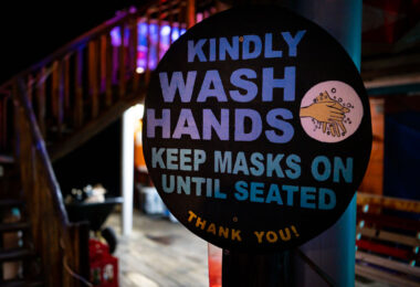 "Kindly wash hands keep masks on until seated Thank you" sign outside a restaurant in San Pedro, Belize.