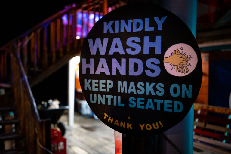 COVID-19 sign in Belize 2 "Kindly wash hands keep masks on until seated Thank you" sign outside a restaurant in San Pedro, Belize.