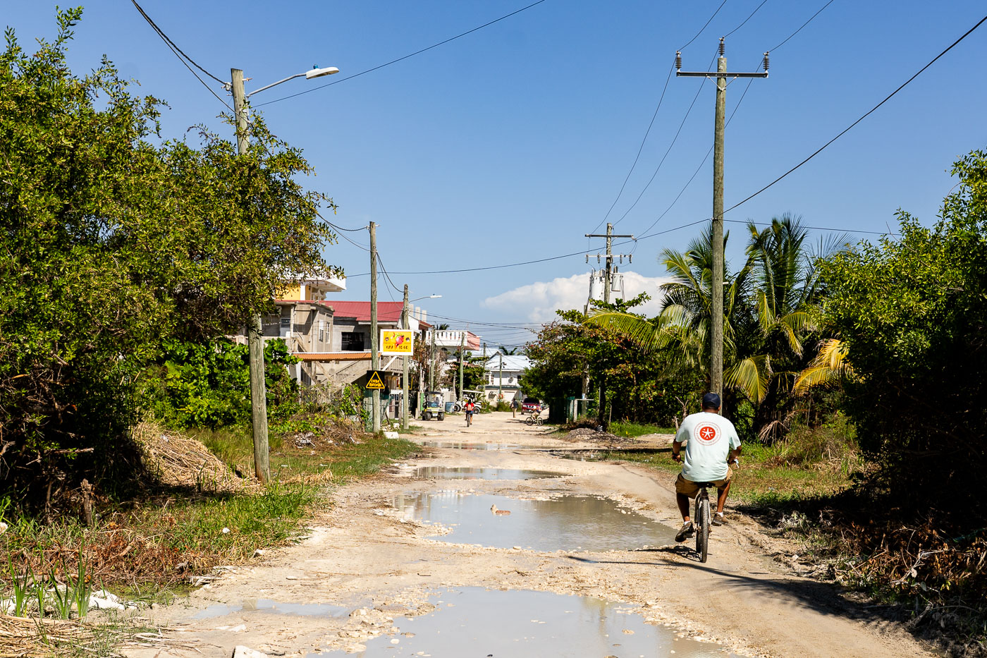 A cyclist rides on a waterlogged, unpaved street in San Pedro, Belize, on Ambergris Caye, where bicycles are a common mode of transport.