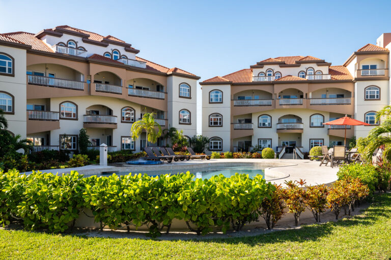 Grand Caribe Belize pool 4 The central pool area at Grand Caribe Belize, a large condominium resort located just north of San Pedro on Ambergris Caye. Built in the mid-2000s and expanded over the following decade, the property is known for its Mediterranean-inspired architecture—arched balconies, stucco facades, and red tiled roofs—adapted for the island’s coastal climate. The interconnected pool system is one of the resort’s signature features, designed to serve the multiple residential buildings that form a semicircle around the courtyard. This part of the island has seen substantial development since the early 2000s, with resorts like Grand Caribe playing a major role in shaping the tourism corridor along the island’s northern shoreline.