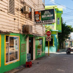 A Belikin beer sign hangs above the entrance to Maha Store in the center of San Pedro on Ambergris Caye. Small neighborhood shops like this one are common throughout the town, serving residents and visitors who travel mostly by golf cart along the island’s narrow streets. The weathered wood siding and bright paint reflect the practical, improvised architecture typical of older commercial buildings in San Pedro, where businesses often blend retail, rentals, and daily essentials in a single storefront.