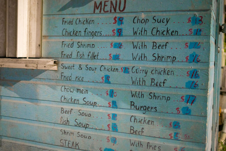 San Pedro, Belize Menu: Fried Chicken, Chop Suey, Burgers 2 A hand-painted menu board displays a variety of food items offered at a casual eatery in San Pedro, Ambergris Caye, Belize. The menu features popular dishes such as fried chicken, chop suey, burgers, and various soups and seafood options, with prices indicated in Belizean dollars. This type of open-air food stall is common in tourist destinations and local communities throughout Belize, providing accessible and affordable meals. The simple, rustic presentation of the menu reflects the laid-back atmosphere often found in coastal towns like San Pedro.