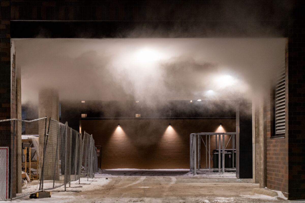 Steam rising between construction fences in Minneapolis, Minnesota, on a freezing winter night.