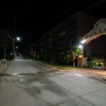 Mara Laguna Resort illuminated along the main north road in San Pedro, Ambergris Caye. The complex sits just across from the lagoon side of the island, a short distance from the town center, and is known for its residential condos and easy access to both the waterfront and nearby businesses. This nighttime view highlights the quiet stretch of road leading past the entrance, a scene typical of the calmer hours on the north side of the island.