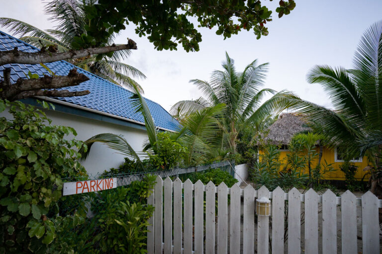 Parking Sign at John's Escape, Ambergris Caye, Belize 3 A white parking sign with orange lettering is affixed to a fence at John's Escape Bar and Grill on Ambergris Caye, Belize.