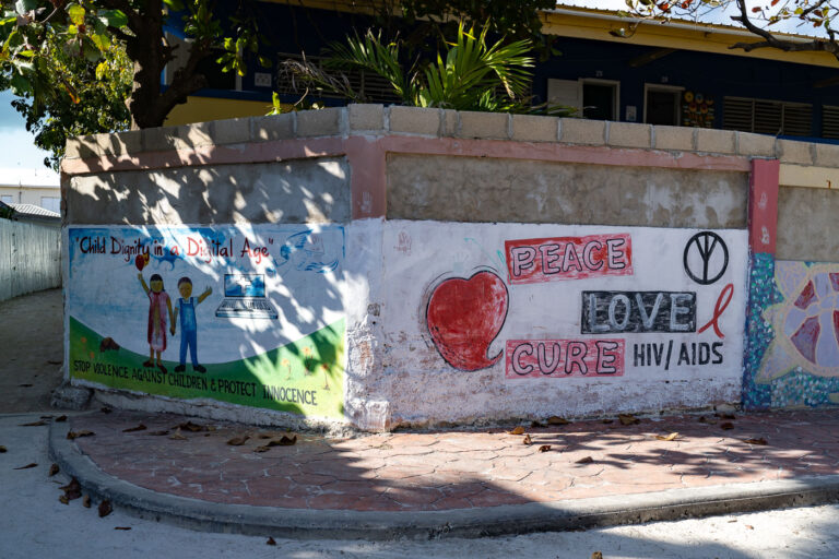 Peace Love Cure HIV AIDS mural in Belize 2 A street mural in San Pedro, Belize, promotes children’s protection and HIV/AIDS awareness, illustrating the community’s grassroots approach to social health education. Murals like this are part of a broader island effort to encourage public engagement and advocate for youth safety and digital awareness in a growing tourism economy that still values close-knit community identity.
