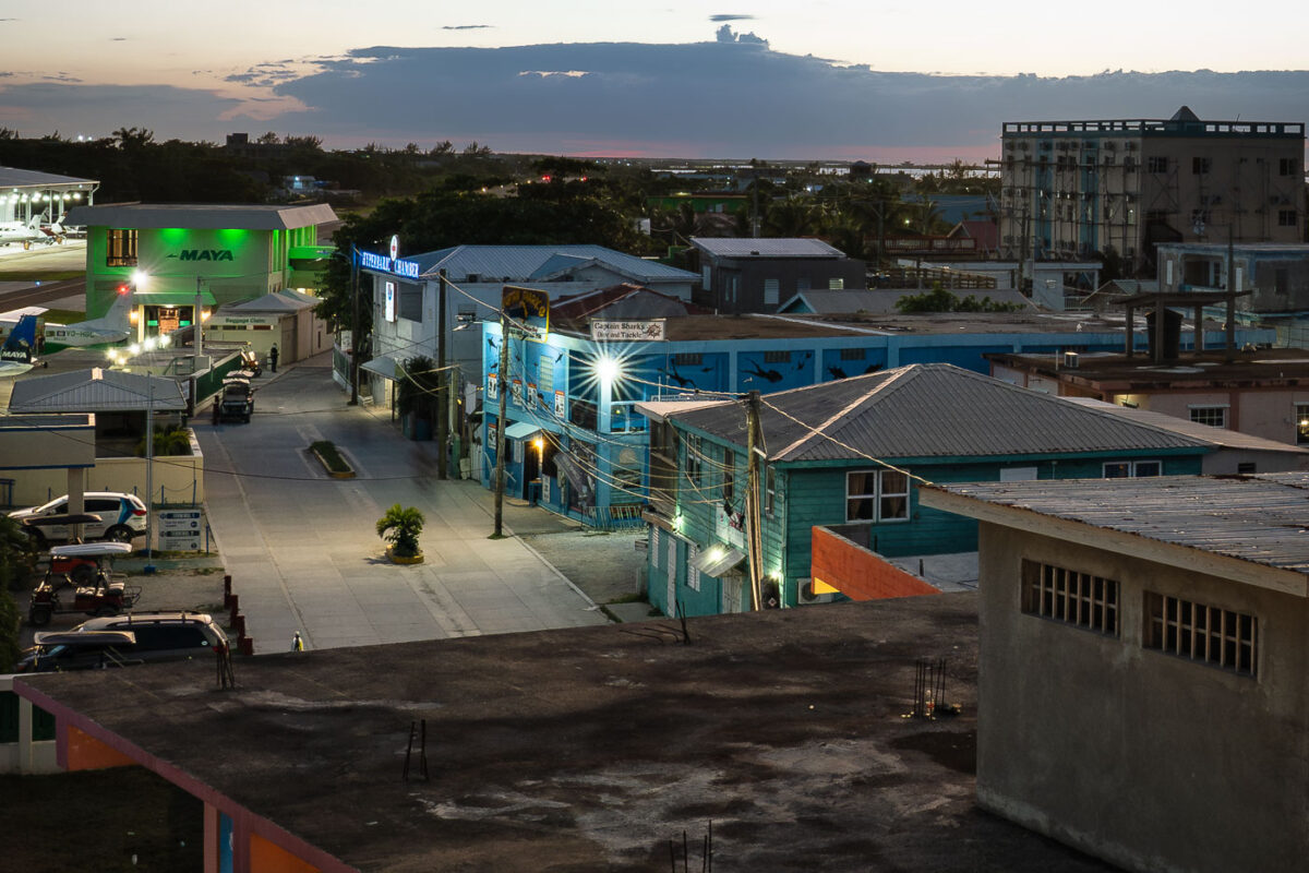 Dusk settles over San Pedro, Belize, illuminating the town and its airstrip, a vital link for Ambergris Caye. Maya Island Air planes are visible.
