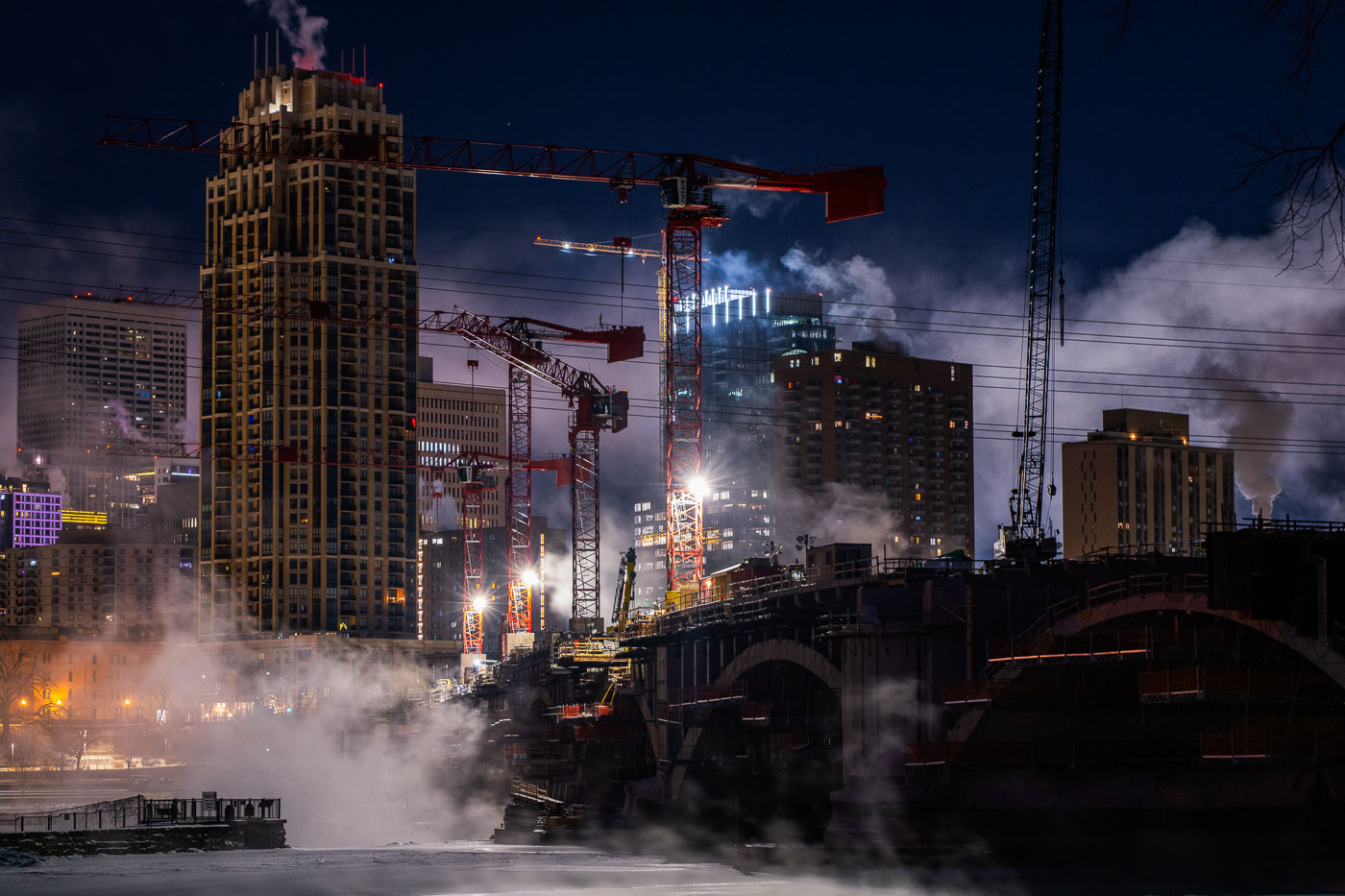 Steam and tower cranes on a frigid night