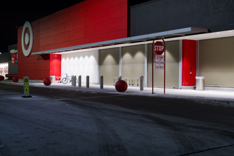 Target East Lake Street with Security Shutters Lowered 1 The Target store on East Lake Street in Minneapolis is shown with its security shutters lowered. This location became a focal point during the 2020 Minneapolis uprising following the murder of George Floyd. The building across the street housed the Minneapolis Police Department's Third Precinct, which was overrun and set ablaze by protesters. The lowered shutters suggest a period of closure or heightened security in response to the unrest.