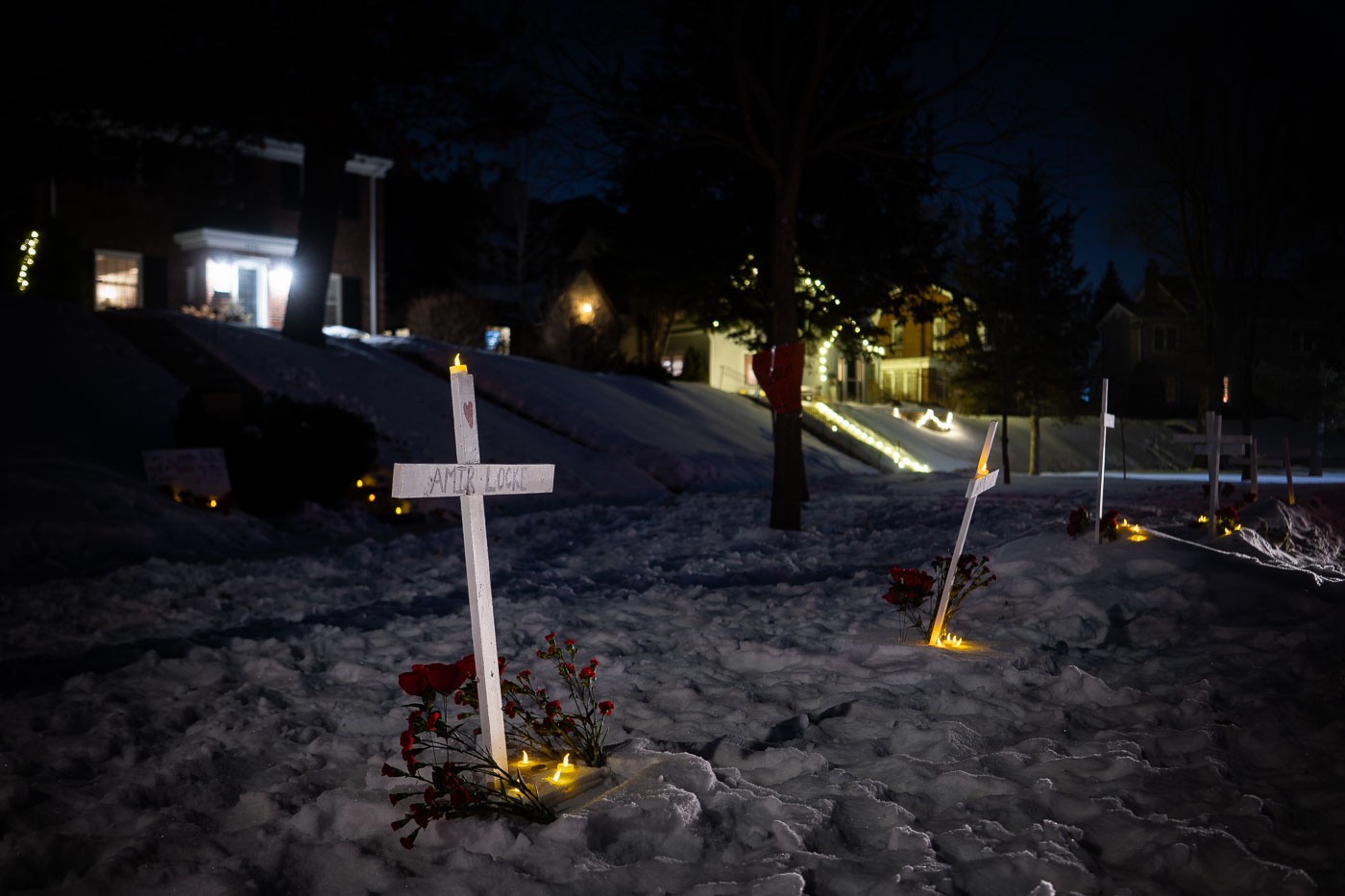 A makeshift memorial for Amir Locke, who was killed by Minneapolis Police, is seen outside the home of the Minneapolis Police Chief in Minneapolis, Minnesota. The memorial, consisting of crosses, candles, and flowers, was established following a protest demanding accountability for Locke's death. Despite frigid temperatures with a windchill of -7°F, activists gathered to honor Locke and voice their demands for justice.