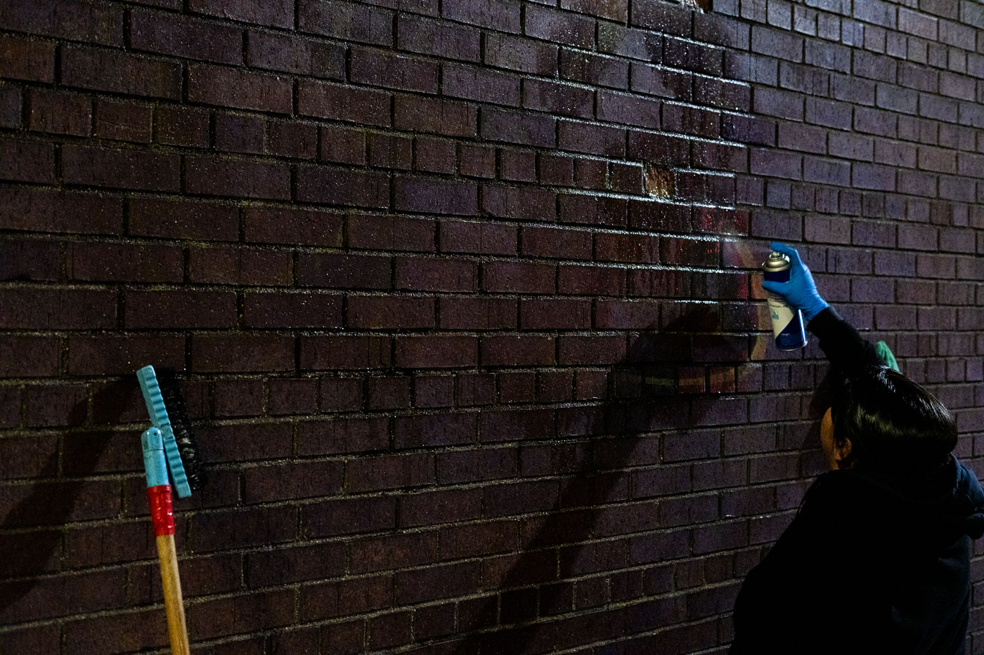 A worker cleans graffiti from a brick building in downtown Minneapolis. The graffiti appeared on the building following protests over the death of Amir Locke, a 22-year-old Black man killed by Minneapolis police during a no-knock warrant execution in February 2022. The incident prompted widespread protests and calls for police reform in the city. The removal of graffiti is part of the city's efforts to restore public spaces after periods of unrest.