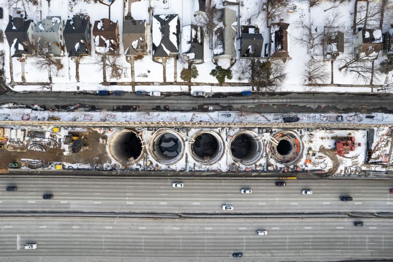 Five Shaft Openings Above I-35W, Stormwater Storage Facility, Minneapolis 3 Aerial view of I-35W stormwater storage tunnel construction showing five large circular pipe sections and surrounding roadway.