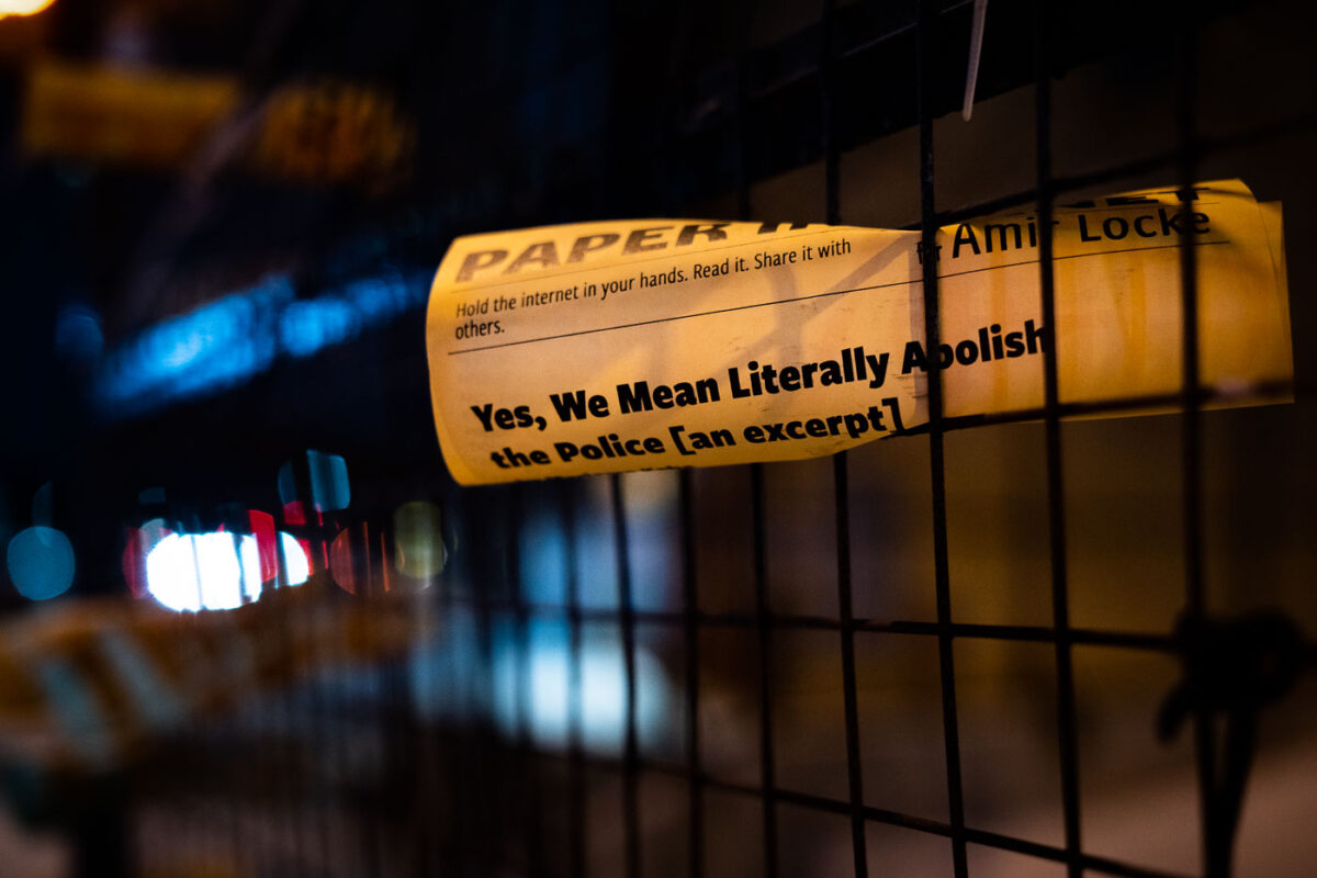 Flyers advocating for police abolition and referencing Amir Locke are posted on fencing at the Minneapolis Police 3rd Precinct.