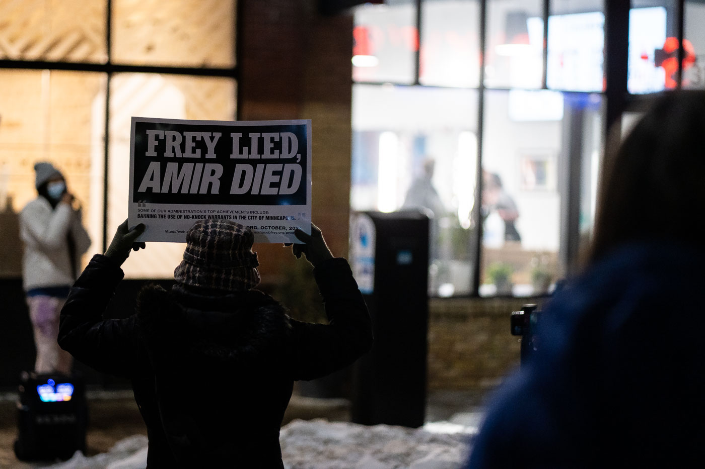 Protesters gathered outside the Minneapolis Mayor's home, holding signs that read "Frey Lied, Amir Died." This protest was in response to the death of Amir Locke, who was killed during a police raid in February 2022. The sign also references "Banning the Use of No-Knock Warrants in the City of Minneapolis," an action taken by Mayor Jacob Frey's administration in response to public outcry following Locke's death. This event highlights ongoing tensions and calls for accountability within the Minneapolis community regarding police conduct and the use of force.
