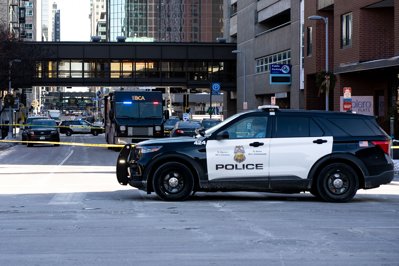 Police vehicles and a Bureau of Criminal Apprehension (BCA) truck are present outside Bolero Flats on Marquette Avenue in Downtown Minneapolis following an officer-involved shooting. The incident occurred on the 7th floor of the apartment building, where an officer reportedly shot and killed a man who was holding a gun. The Minneapolis Police Department, with assistance from the BCA, responded to the event, which took place in a densely populated urban environment. Bolero Flats is a residential building located in the heart of Minneapolis's downtown core.