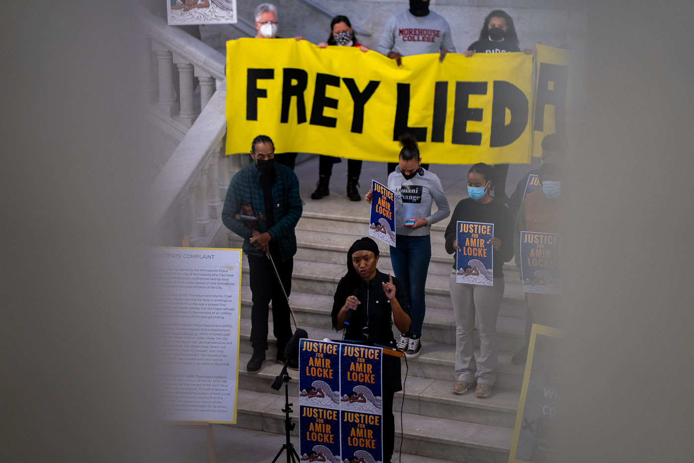 Protesters gathered on the steps of Minneapolis City Hall to protest the police shooting death of Amir Locke. A large banner reading "FREY LIED" was displayed, referencing Mayor Jacob Frey. Demonstrators held signs with "JUSTICE for Amir Locke" and presented ethics complaints against the mayor to the city attorney's office. The event occurred following the February 2, 2022, shooting of Locke by Minneapolis Police officers during a no-knock warrant execution.