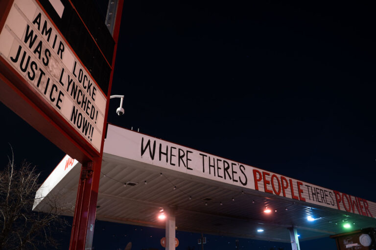 George Floyd Square: Amir Locke Justice Now Sign 2 A sign at George Floyd Square in Minneapolis reads "AMIR LOCKE WAS LYNCHED! JUSTICE NOW!!" The phrase "WHERE THERE'S PEOPLE THERE'S POWER" is spray-painted on the canopy of a nearby structure. George Floyd Square became a focal point for protests following the murder of George Floyd in May 2020 and has since been a site of ongoing activism and community organizing. Amir Locke, a Black and Indigenous man, was killed by Minneapolis police during a no-knock warrant raid in February 2022, sparking renewed calls for justice and police reform.