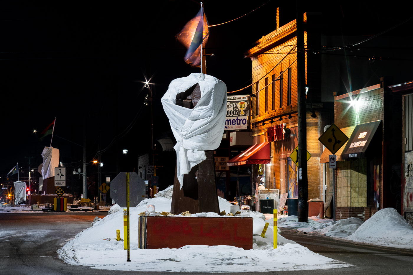 Five raised fist sculptures, memorials to George Floyd and Amir Locke, stand covered in snow at George Floyd Square in Minneapolis. The intersection, which became a focal point for activism and remembrance following the murder of George Floyd in 2020 and the killing of Amir Locke in 2022, has remained a site for community mourning and protest. Although the square was reopened to traffic in June, it continues to serve as a space for public expression and remembrance.