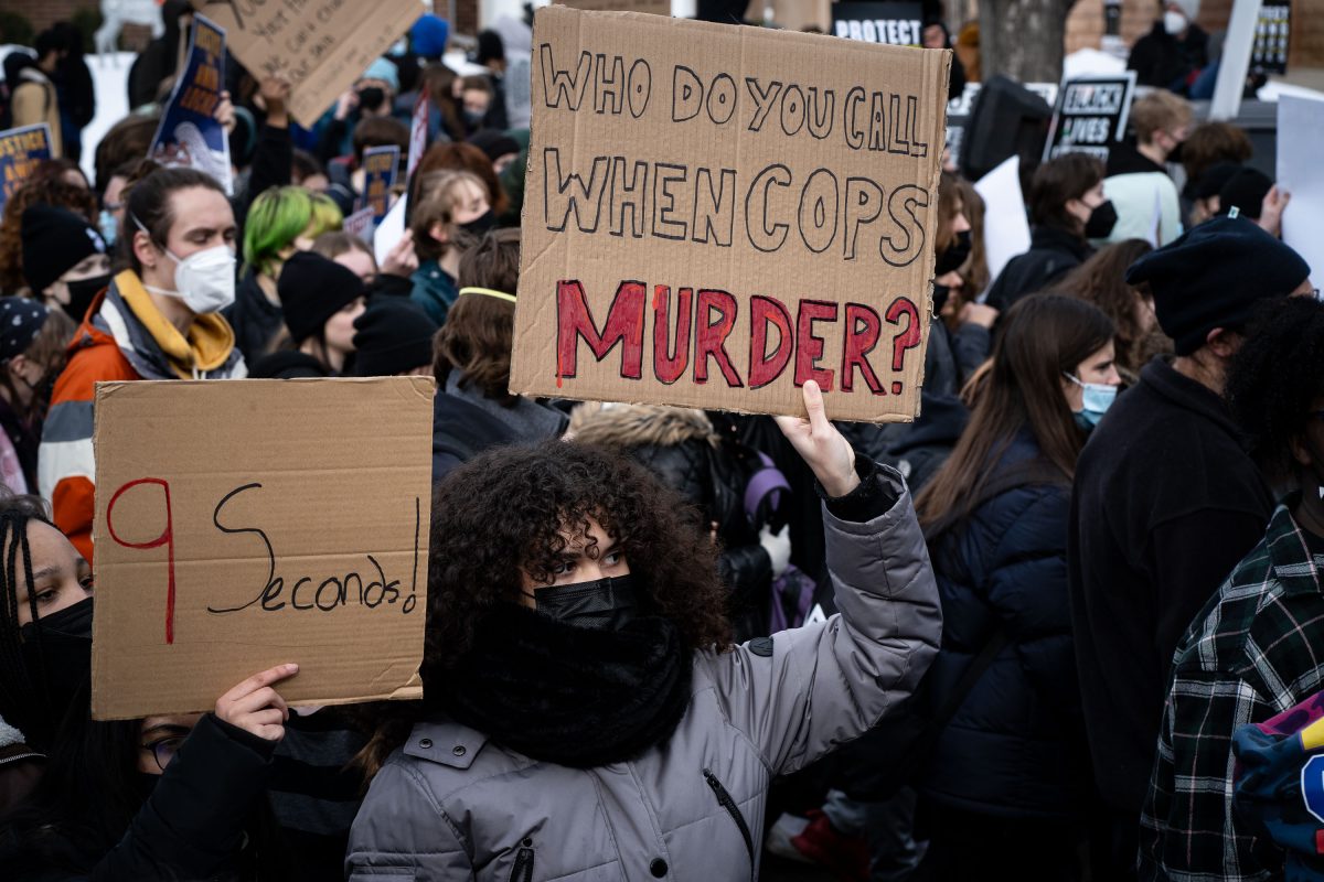 Students hold protest signs after Amir Locke killing