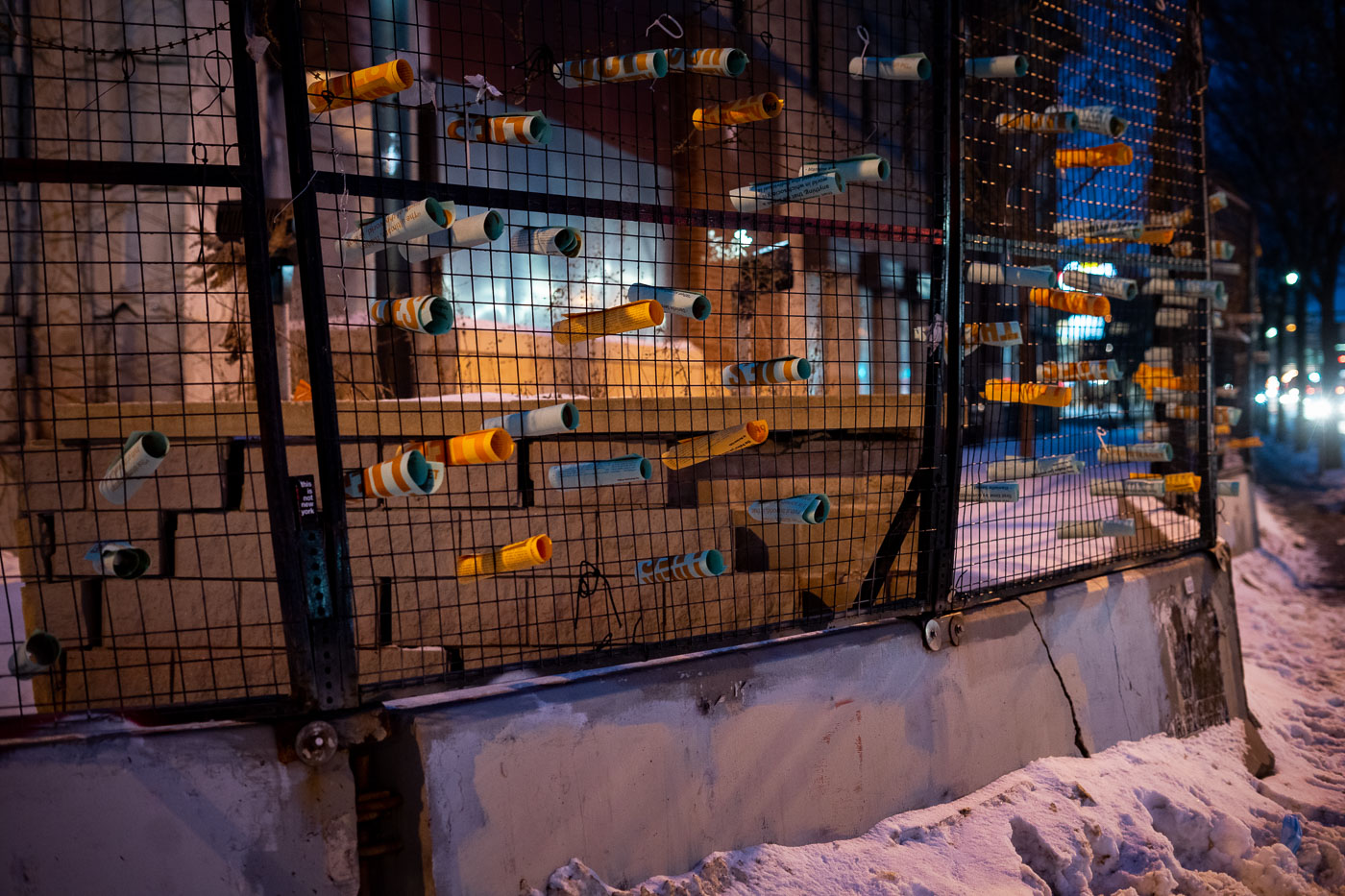 The former Minneapolis Police Third Precinct, damaged during protests in May 2020, is shown barricaded and adorned with flyers. These materials, including an opinion piece by Mariame Kaba titled "Yes, We Mean Literally Abolish The Police," originally published in The New York Times on June 12, 2020, signify the ongoing public discourse and protest following the precinct's destruction. The presence of these flyers on the barricade of the damaged building serves as a visual marker of the events and sentiments that transpired in Minneapolis.