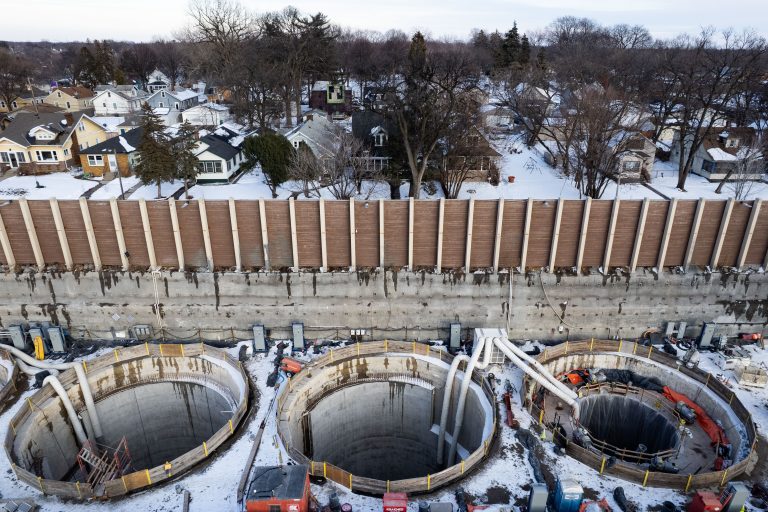 Three Shaft Openings Beside Residential Blocks, I-35W Stormwater Storage Facility 4 Aerial view of I-35W stormwater storage tunnel construction showing three large circular concrete sections under a wooden barrier