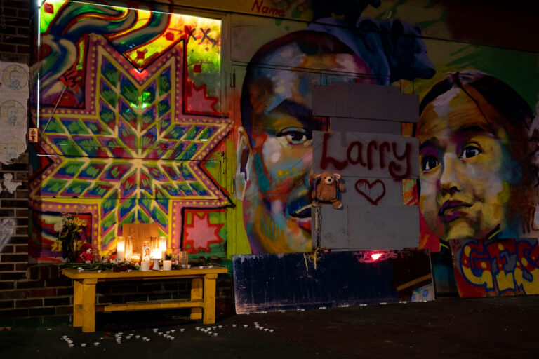 George Floyd Square: Memorial for Larry Mosby, Minneapolis 3 A memorial for Larry Mosby is displayed at George Floyd Square in Minneapolis. Mosby died a week prior to this photograph, inside the occupied space. The memorial features portraits of Mosby and other individuals, along with candles and flowers, set against vibrant murals that have become a hallmark of the square. George Floyd Square has served as a significant site of protest and remembrance since the murder of George Floyd in May 2020.