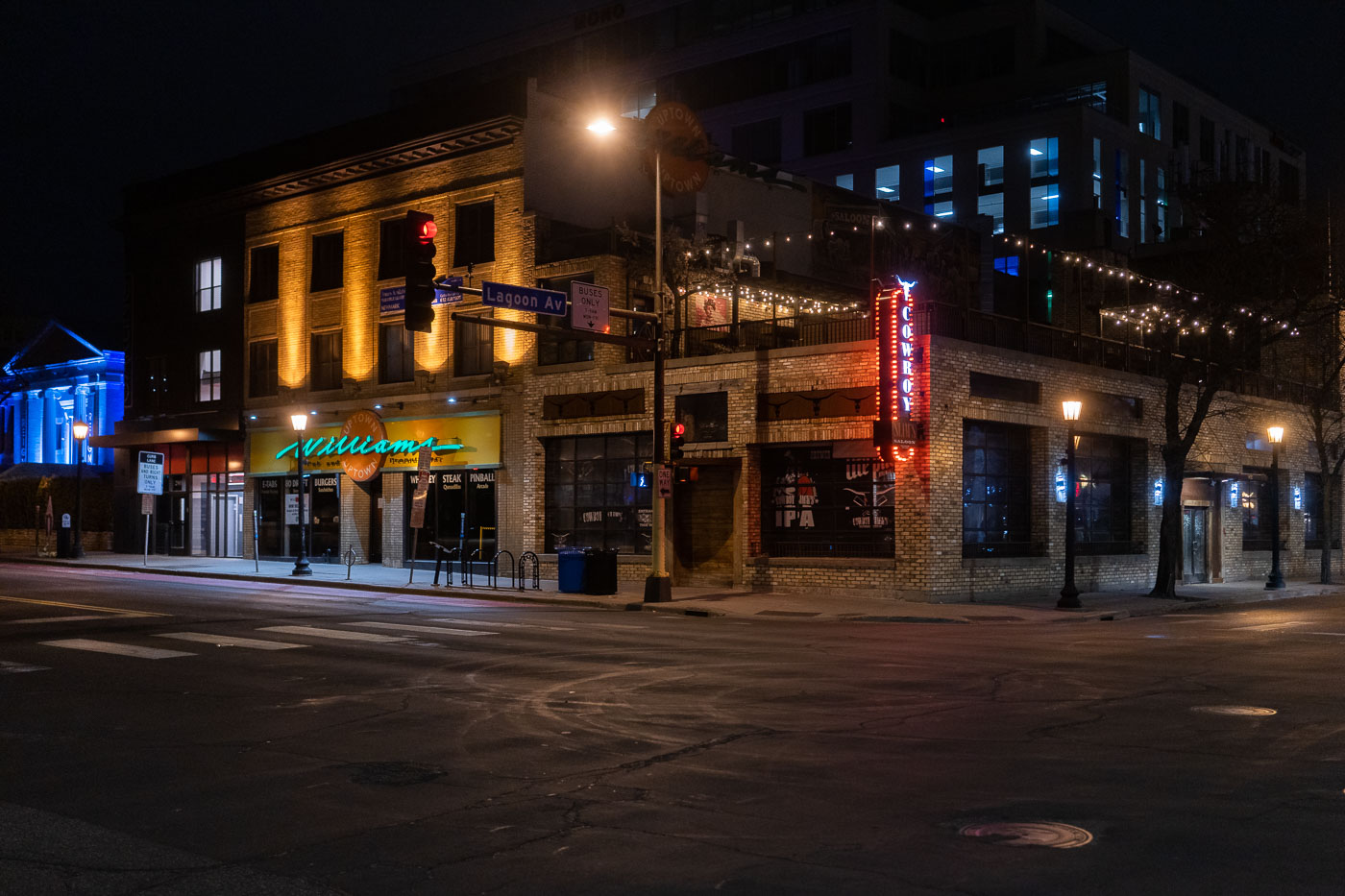 Cowboy Slim's and Williams Uptown are illuminated at night on the corner of Hennepin Avenue and Lagoon Avenue in Minneapolis's Uptown neighborhood. Cowboy Slim's, a bar and saloon, features prominent neon signage, while Williams Uptown, a food and drink establishment, is lit by its facade. This corner has long served as a commercial and entertainment hub within Uptown, known for its vibrant nightlife. The businesses at this location contribute to the area's reputation as a popular destination for dining and socializing.